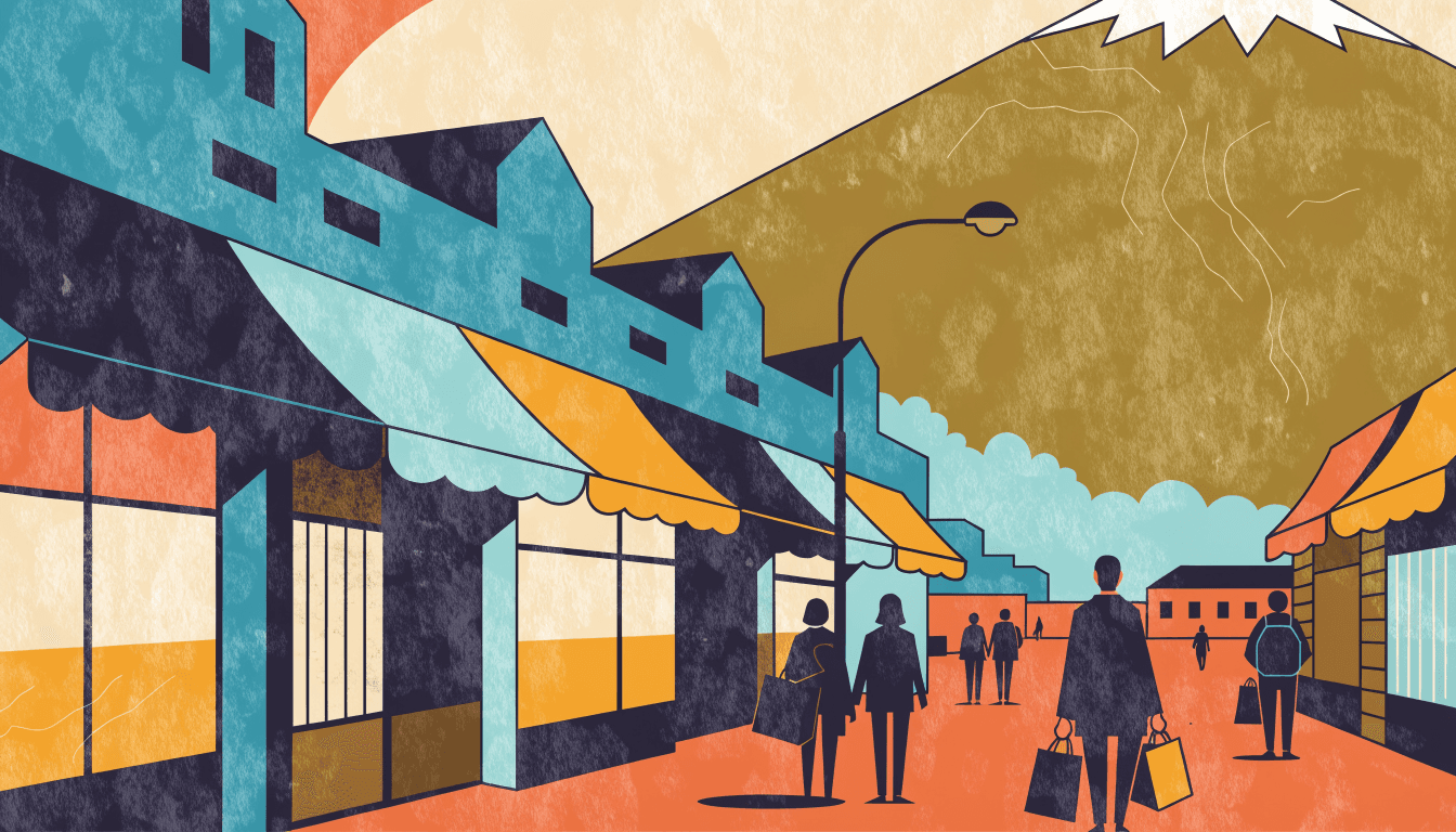 An open-air outlet promenade in autumn, awning-fronted shops on one side, shoppers with bags walking toward a mountain with a snow-capped peak.